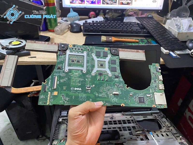 Kỹ thuật viên tháo rời mainboard laptop để vệ sinh bụi và tra keo tản nhiệt mới
