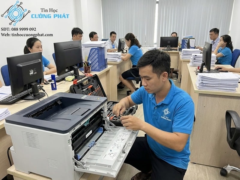Kỹ thuật viên Tin Học Cường Phát đang nạp mực và sửa máy in tận nơi tại một văn phòng bận rộn ở Quận Tân Phú.
